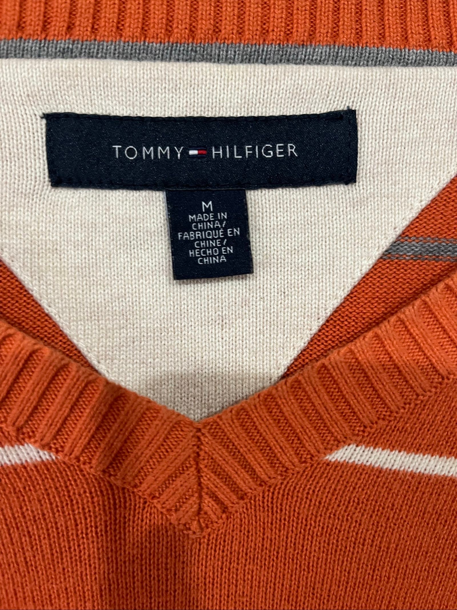 Tommy Hilfiger men's grey and white striped v-neck sweater with embroidered flag logo.