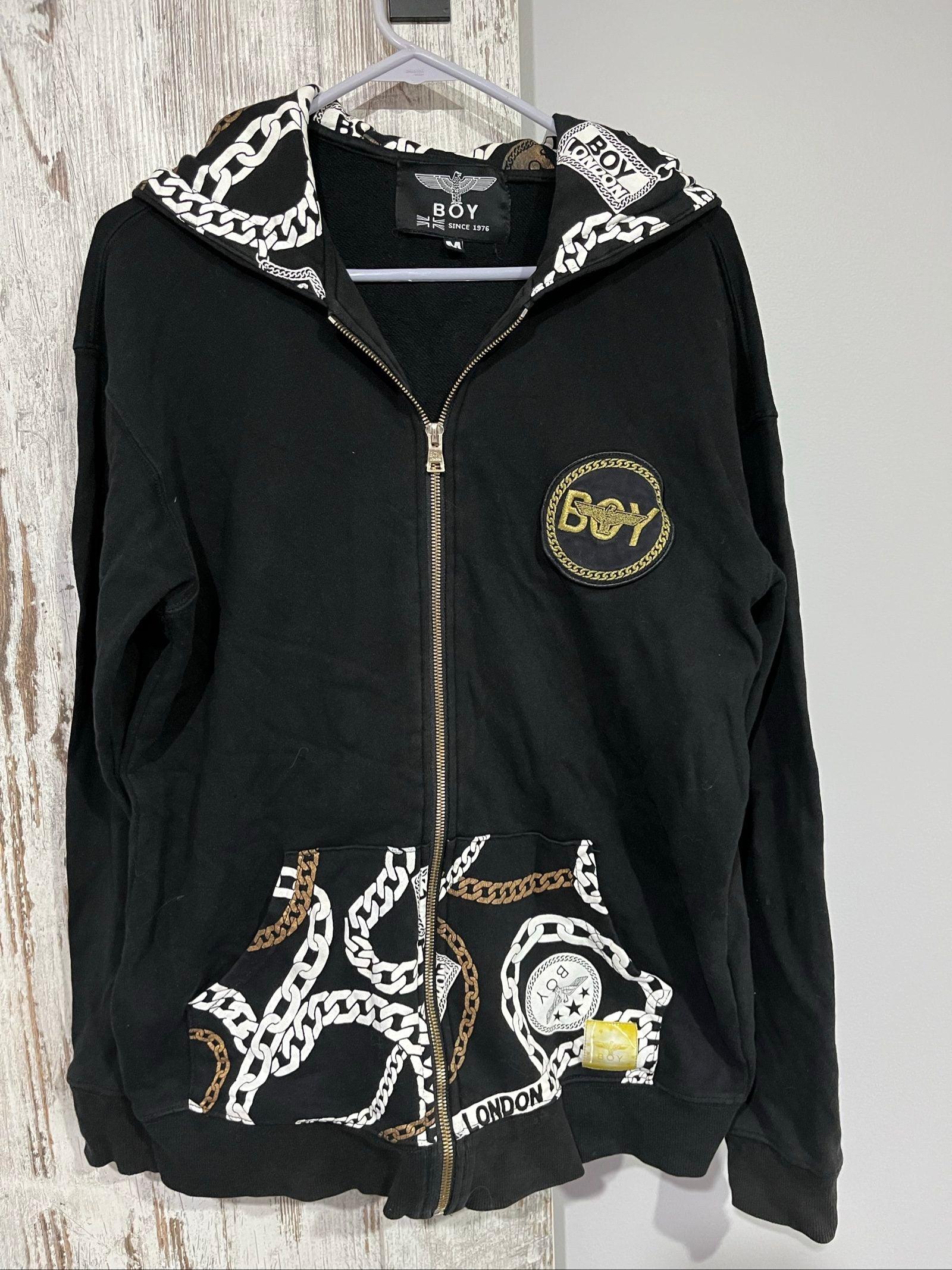 Boy London black zip-up hoodie with gold chain print and logo patch details.