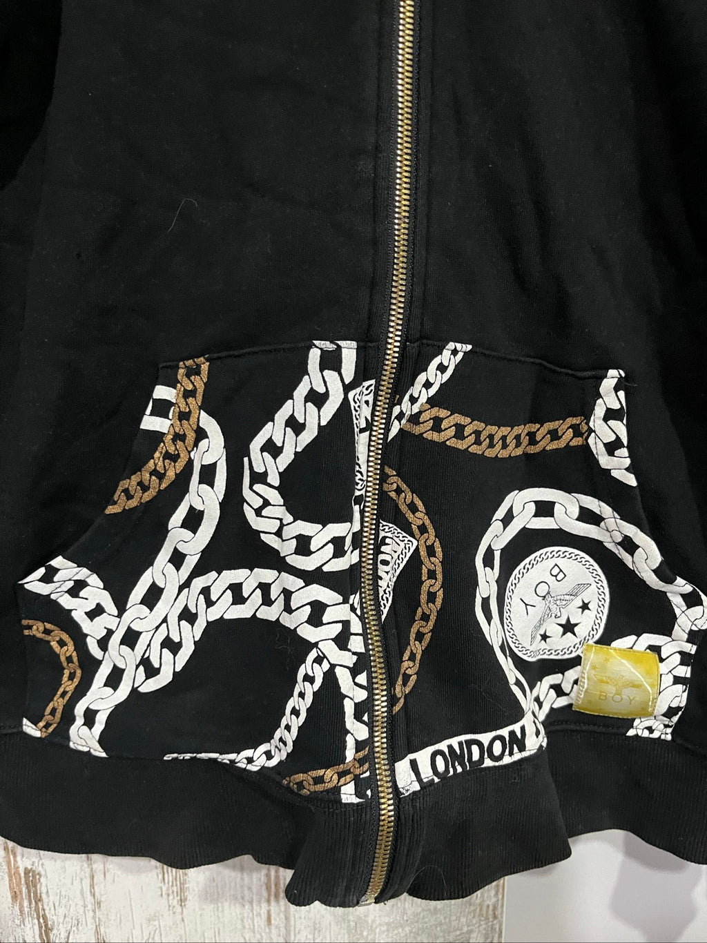 Boy London black zip-up hoodie with gold chain print and logo patch details.