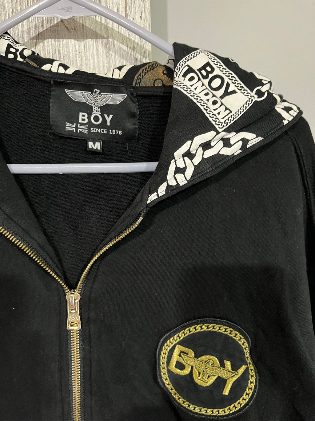Boy London black zip-up hoodie with gold chain print and logo patch details.