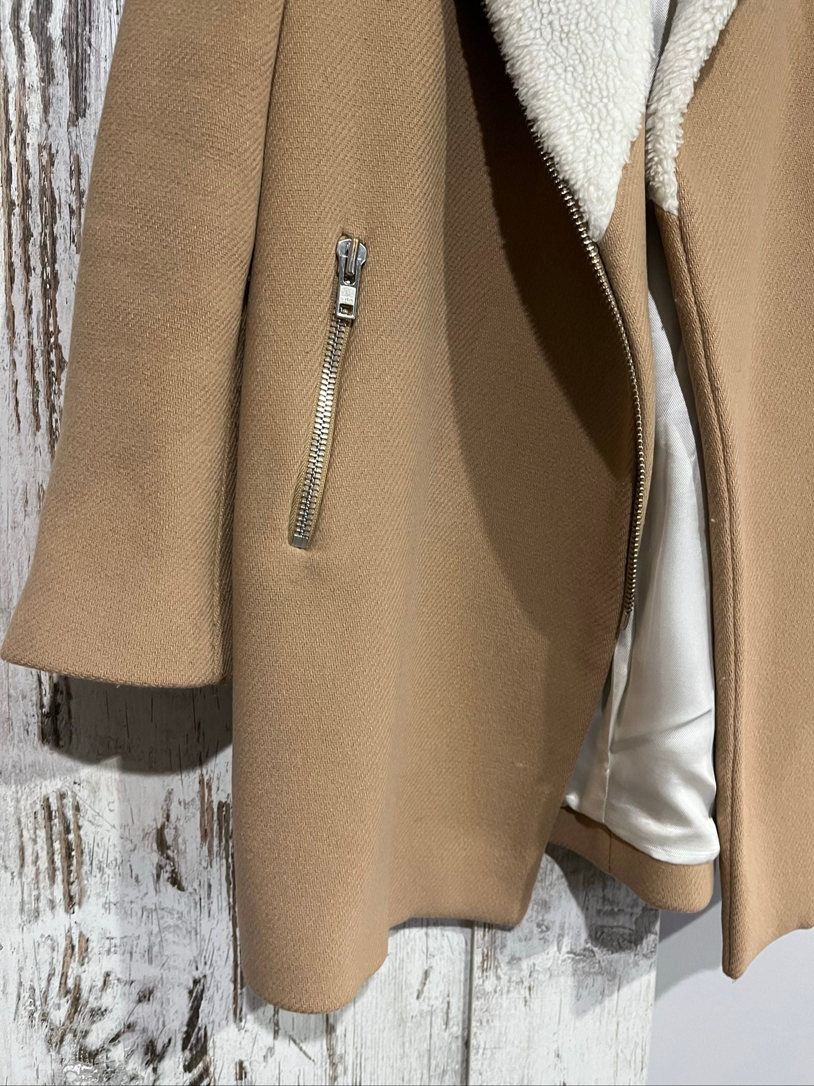 Sandro camel coat with white faux shearling collar and silver-tone zipper pockets.