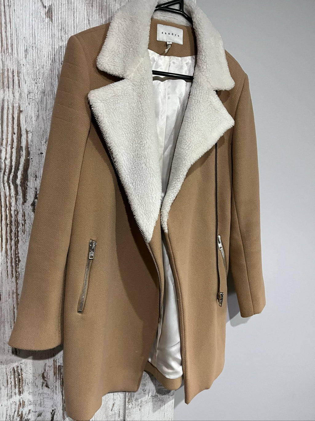 Sandro camel coat with white faux shearling collar and silver-tone zipper pockets.