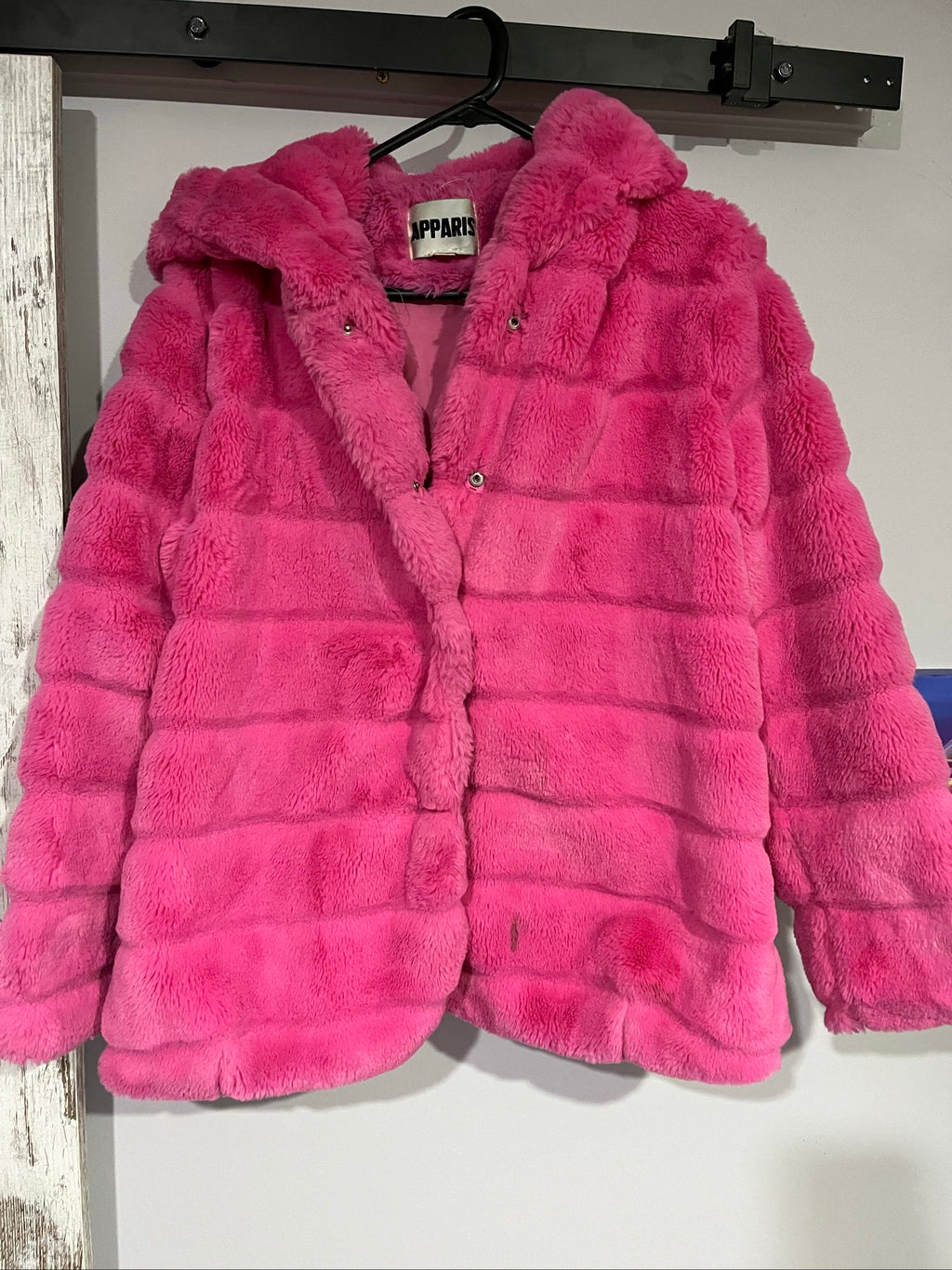 Apparis pink faux fur hooded jacket with snap-button closures and plush texture.