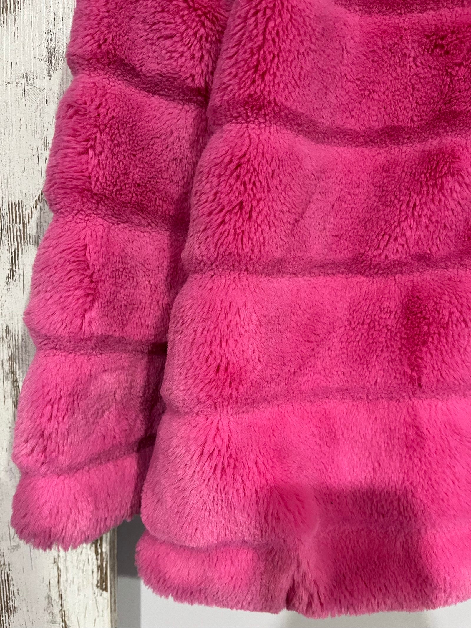 Apparis pink faux fur hooded jacket with snap-button closures and plush texture.
