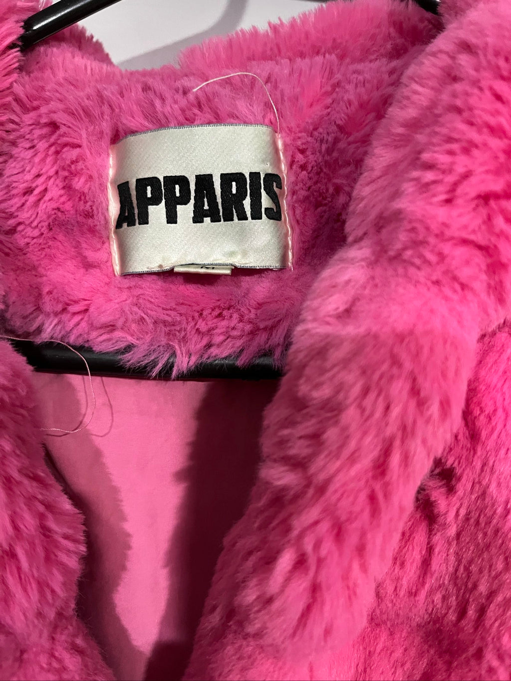 Apparis pink faux fur hooded jacket with snap-button closures and plush texture.