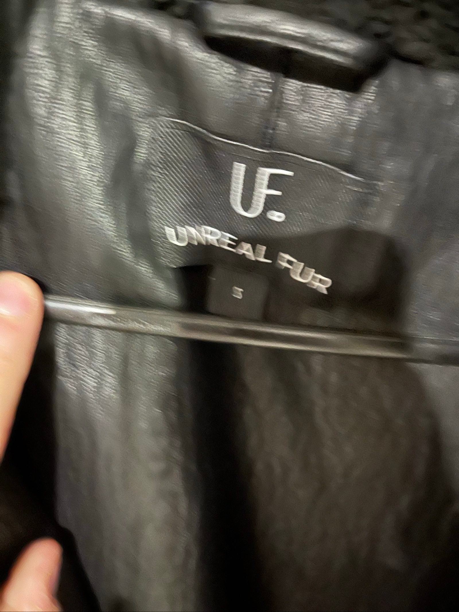 Unreal Fur black vegan shearling jacket with zip front, shearling cuffs, and buckle detail.