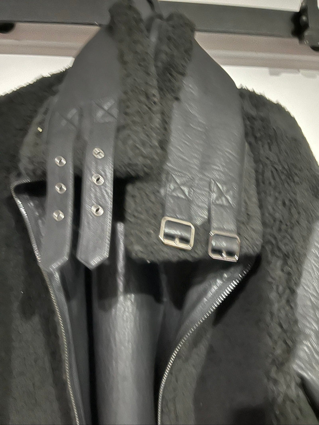 Unreal Fur black vegan shearling jacket with zip front, shearling cuffs, and buckle detail.